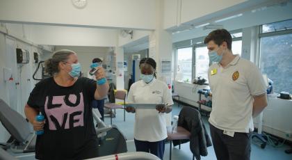 Physios checking on a patient while they exercise with small hand weights