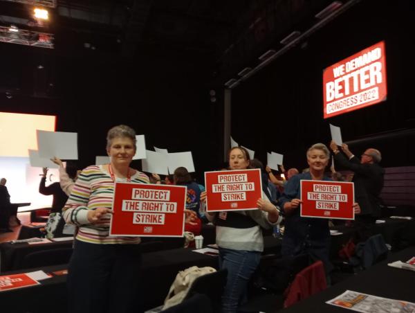 Alex MacKenzie, Helen Lewes, and Helen Purcell stand on the floor of congress, each holding placards reading 'protext the right to strike'